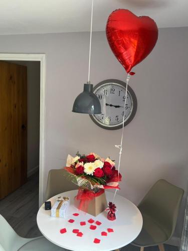 a heart balloon and a table with flowers and a clock at Lake District and Eden Valley Thornhill Lodge in Long Marton