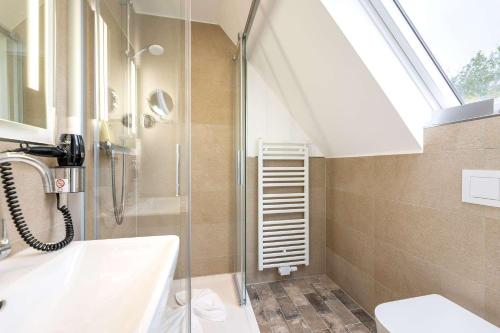 a bathroom with a shower and a sink and a skylight at Hotel Südblick in Norderney
