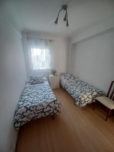 1 dormitorio con 2 camas, silla y ventana en APARTAMENTO VIGO CAMELIAS CENTRO, en Vigo