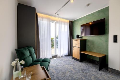 a living room with a green couch and a television at Hotel Südblick in Norderney