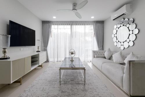 a white living room with a couch and a tv at Modern villa with pool close to the beach - LP #97 in Phuket Town