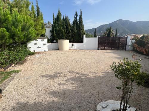 a gravel driveway with trees and a white fence at Vela Luka Frigiliana in Frigiliana