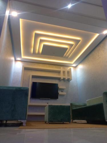 Ouma yanis في القنيطرة: غرفة بها تلفزيون بشاشة مسطحة وكراسي خضراء