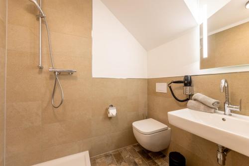 a bathroom with a shower and a toilet and a sink at Hotel Südblick in Norderney