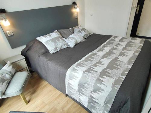 une chambre avec un grand lit et une chaise dans l'établissement Charmant T2 avec balcon pour 2 pers à Cauterets, tout équipé, proche pistes - FR-1-234-306, à Cauterets