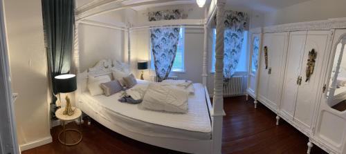 a bedroom with a white canopy bed with blue curtains at Boutique Hotel Postgården in Holsted
