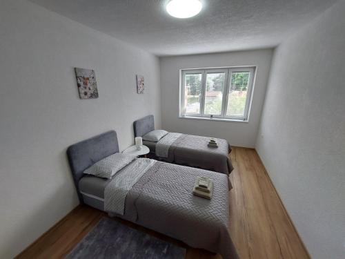 two beds in a room with a window at Apartman "MEDENI" in Bihać