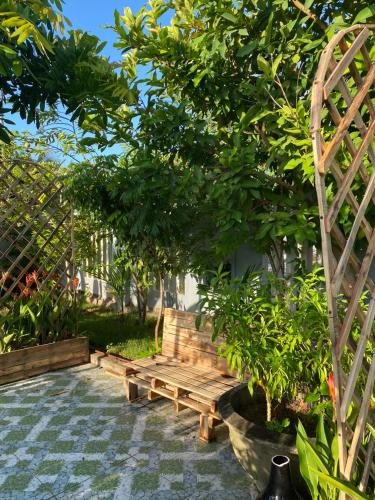 a garden with a wooden bench and a tree at Laoxao Homestay in Hoi An