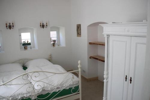 a white bedroom with a bed and two mirrors at Hofmühle Pfaffroda-Ferienwohnung Am Mühlbach in Olbernhau
