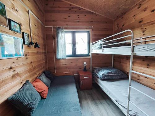 a bedroom with bunk beds in a wooden cabin at Cudnie tu - Noclegi na Kaszubach in Wdzydze Kiszewskie