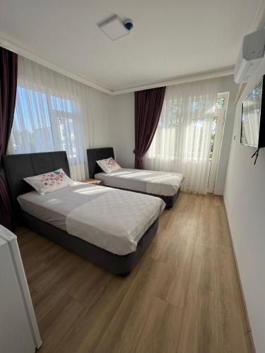 two beds in a room with wood floors and windows at Asimado Hotel in Antalya