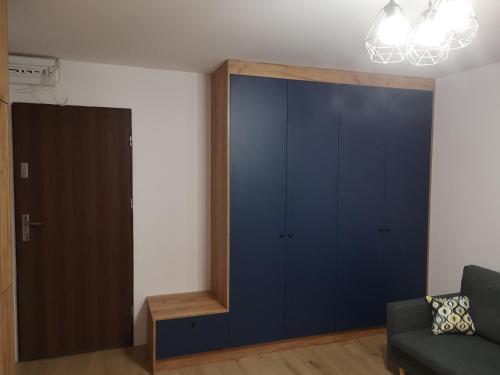 ein Wohnzimmer mit einem blauen Schrank und einem Sofa in der Unterkunft Małe mieszkanie in Łomża