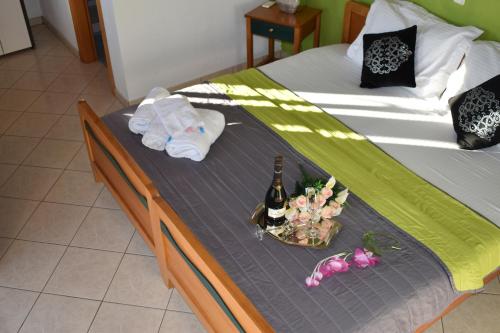 Studios Centro 5 - 2nd Floor في بوتوس: سرير وصينية عليها زجاجات من النبيذ والزهور