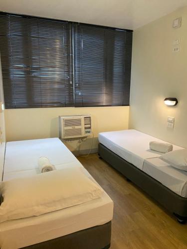 a room with two beds and a fan and window at Burgos Hub Hostel in Manila
