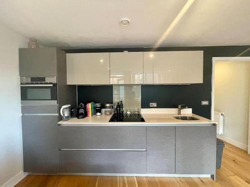 a kitchen with white and gray cabinets and a sink at Modern 1 King Size Apartment in Angel near canal in London