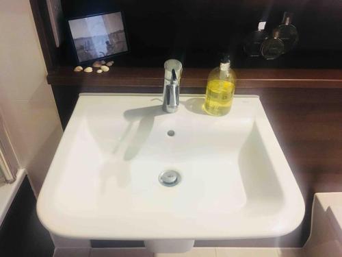 a white bathroom sink with a soap bottle on it at Modern 1 King Size Apartment in Angel near canal in London