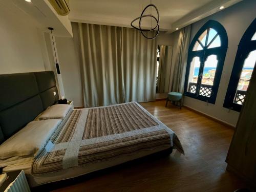 a bedroom with a large bed and two windows at Beautiful Seaview apartment in Tawaya Sahl Hashish in Hurghada