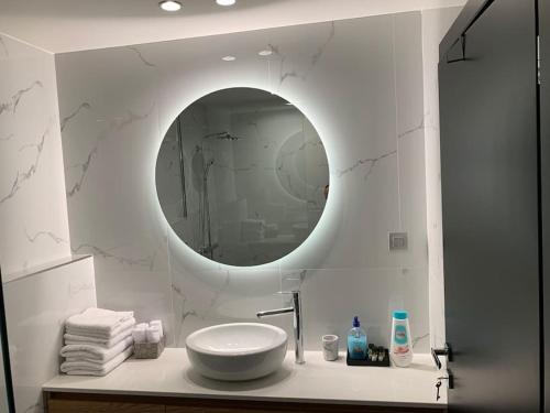 Baño blanco con lavabo y espejo en Above & Beyond Volos City Center Luxury Redefined, en Volos