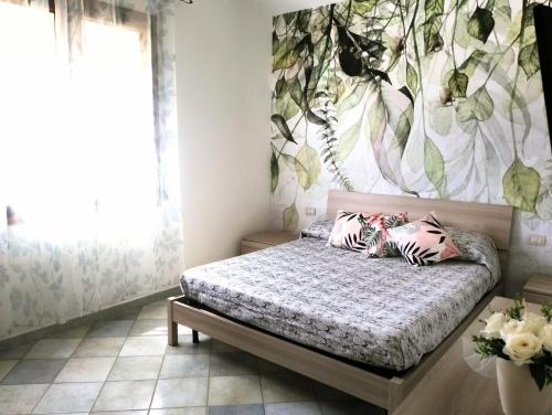 a bedroom with a bed with a flower mural on the wall at Appartamento da Monica in Tortolì
