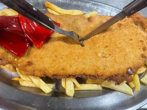 um peixe e batatas fritas num prato com uma faca em Hotel Rural La Corte em Villar de Vildas