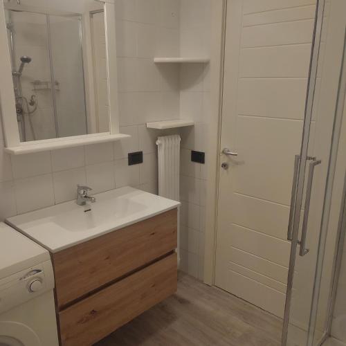 a bathroom with a sink and a shower with a mirror at Appartamento Levico lake in Levico Terme