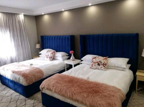 a bedroom with two beds with blue headboards at Shai's Nest in Centurion