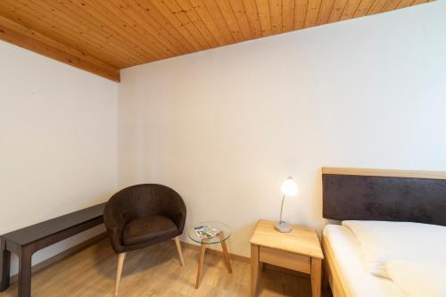 a bedroom with a chair and a bed and a table at Hotel Sonne in Wildhaus