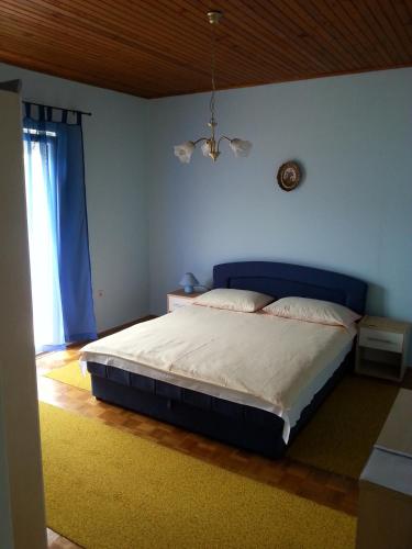a bedroom with a bed with a blue headboard and a window at Apartments Lukacic in Tkon