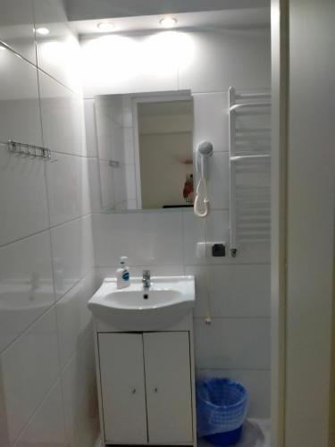 a white bathroom with a sink and a mirror at U Marioli in Junoszyno