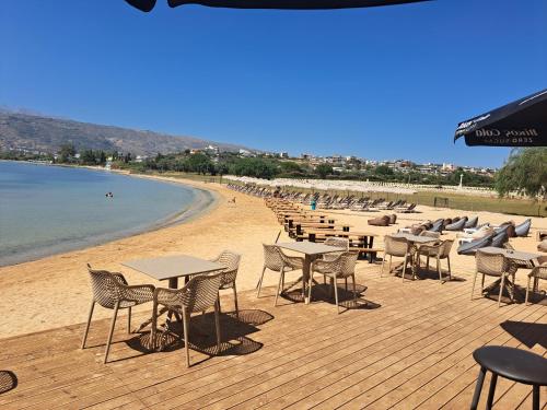 a wooden deck with tables and chairs on a beach at Antigoni Apartment in Souda