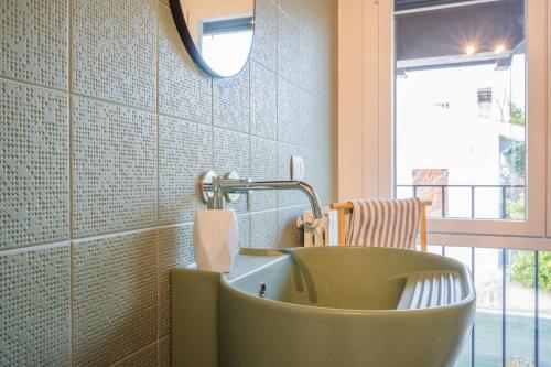 baño con bañera verde y ventana en Cerlino's B&B, en Reggio Emilia