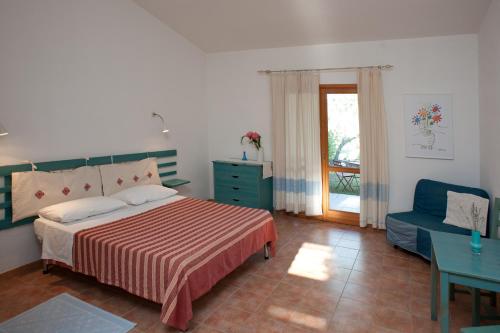 ein Schlafzimmer mit einem Bett, einem Sofa und einem Fenster in der Unterkunft Agriturismo Don Lucifero in Orosei