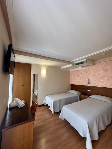 a hotel room with two beds and a desk at Hostal Restaurante Boccalino in León