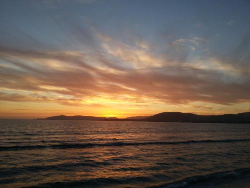 a sunset over the ocean with mountains in the background at Hotel Mistral in Alghero