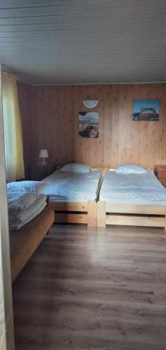 two beds in a bedroom with wooden walls at U Marioli in Junoszyno