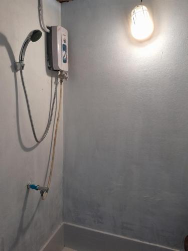 a shower in a bathroom with a light on the wall at Pikban in Chiang Rai