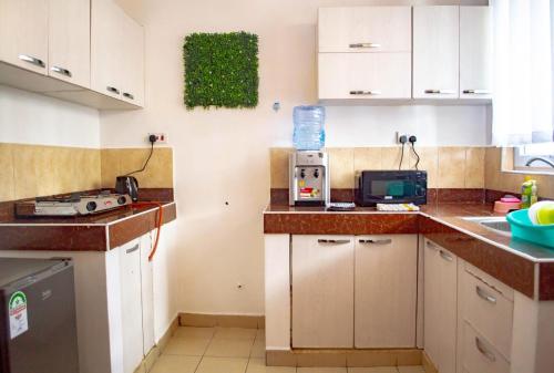 Elle comprend une petite cuisine avec des placards blancs et un évier. dans l'établissement FAHARI .KE 3BR BY MTWAPA HOMESTAY, à Mombasa