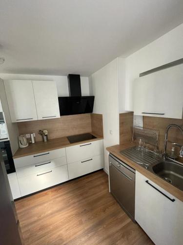 une cuisine avec des armoires blanches et un plancher en bois dans l'établissement Maison hyper-centre Bagnères de Luchon, à Luchon