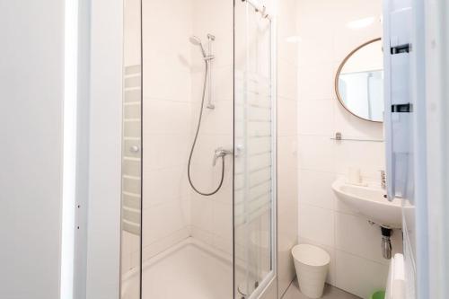 uma casa de banho branca com um chuveiro e um lavatório. em Simply Serene em Viena
