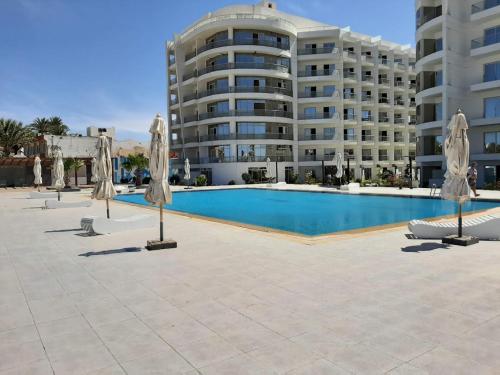 a swimming pool with umbrellas in front of a building at Scandic Resort, free WiFi, sandy beach, coral reef in Hurghada