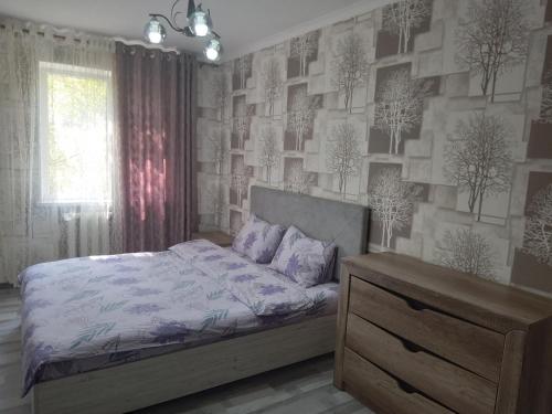 a bedroom with a bed and a wall with trees at Мейкин in Osh