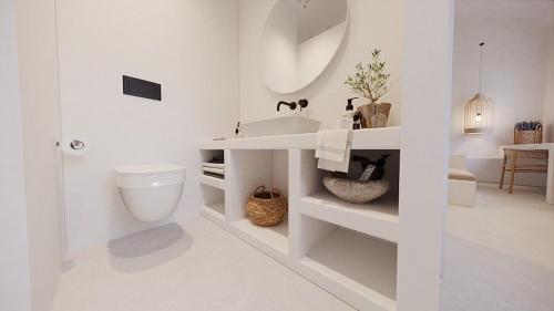 La salle de bains blanche est pourvue d'un lavabo et de toilettes. dans l'établissement Lejardin suites santorini, à Pyrgos