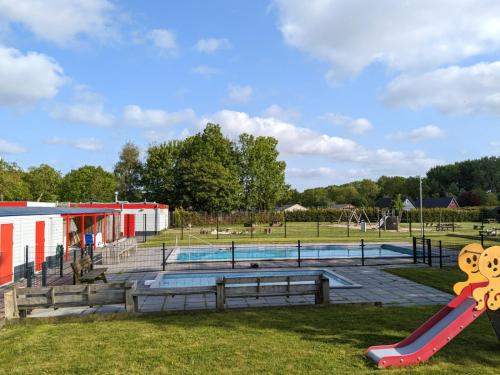 a playground with a pool and a slide at Gemütliches Ferienhaus mit beheiztem Pool, Garten und überdachter Terrasse in Tzummarum
