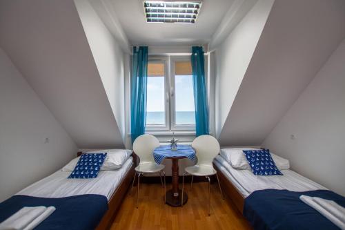 two beds and a table in a room with a window at DALBA pokoje przy samej plaży in Krynica Morska