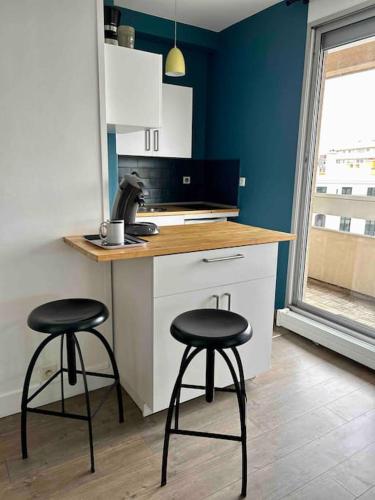 une cuisine avec deux tabourets à un comptoir avec un comptoir dans l'établissement Studio- avec parking- proche Cathedrale, à Reims
