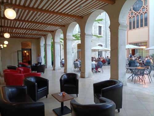 um lobby com cadeiras e pessoas sentadas nas mesas em Hôtellerie Notre Dame de Lumières em Goult