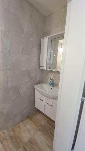 W białej łazience znajduje się umywalka i lustro. w obiekcie Villa Bardha w mieście Struga