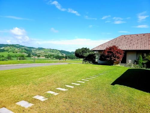 a grassy yard next to a house and a road at Apartma Stanka in Bistrica ob Sotli