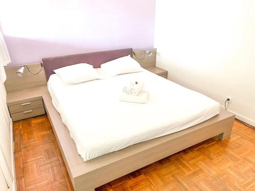a bedroom with a bed with white sheets and a wooden floor at Horizon YourHostHelper in Saint-Laurent-du-Var