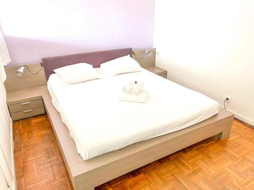 Cette chambre comprend un lit avec des draps blancs et du parquet. dans l'établissement Horizon YourHostHelper, à Saint-Laurent-du-Var